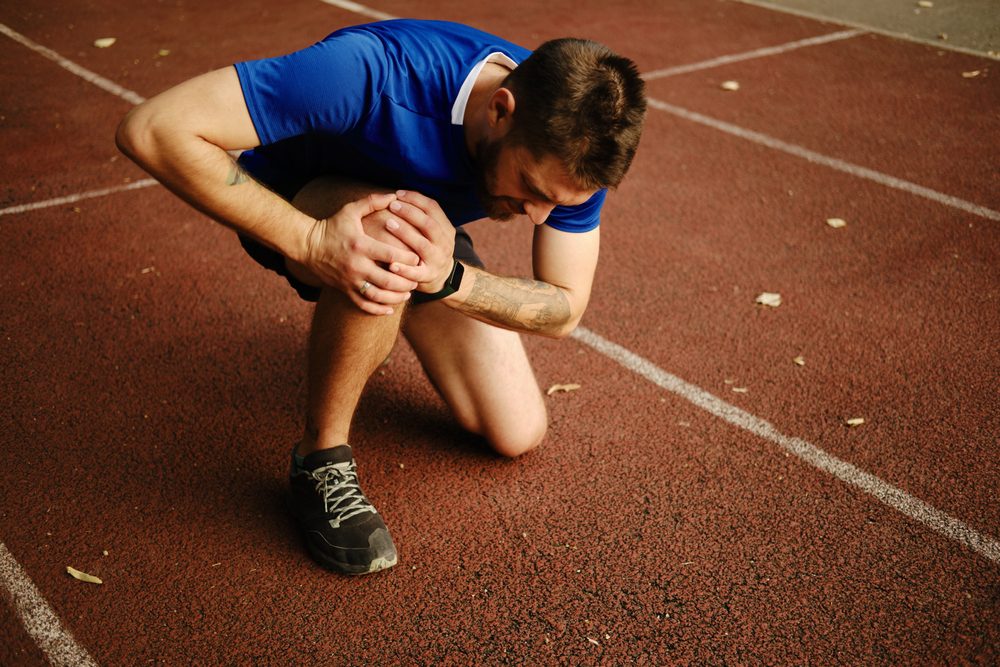 Man holding his knee in pain because he has Infrapatellar Bursitis