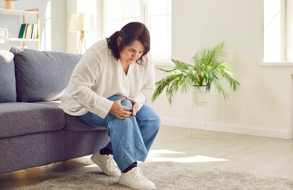 Woman with knee arthritis holding her knee in pain