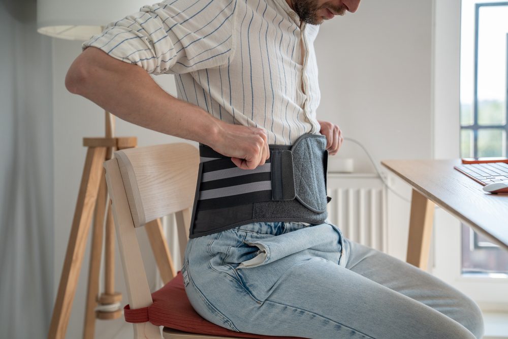 Man using a back brace to help him with his herniated disc