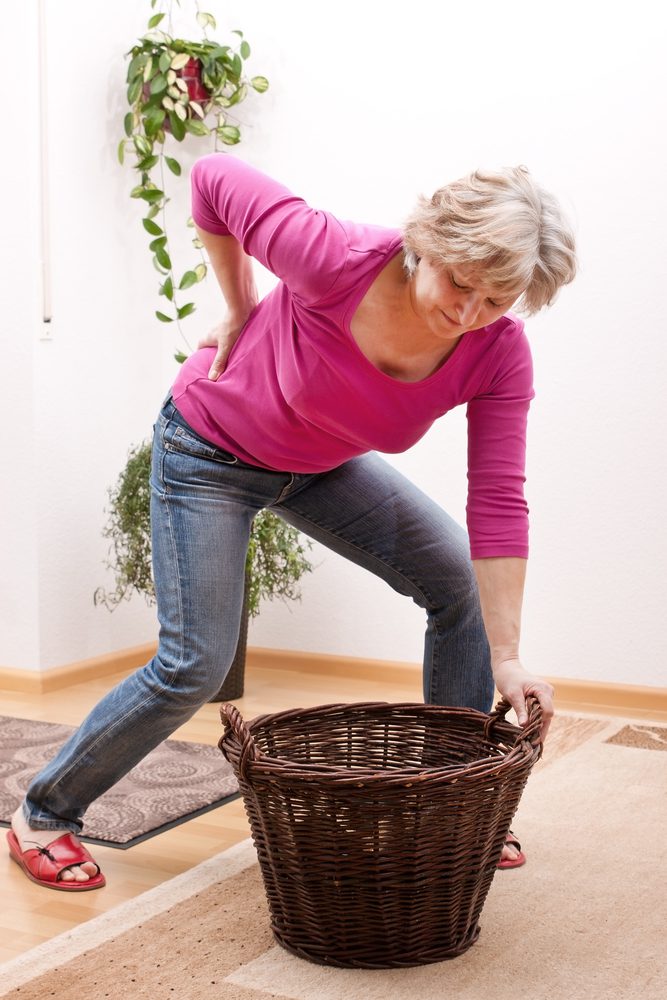 Elderly woman with Herniated disc experiencing pain when bending down to pick up a basket