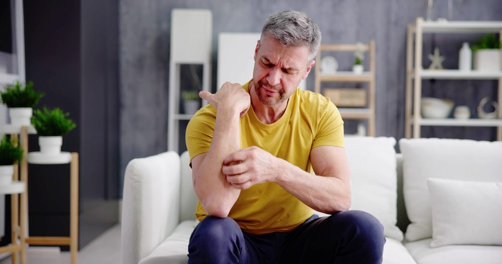 man scratching his arm which does not have a rash but is still itchy