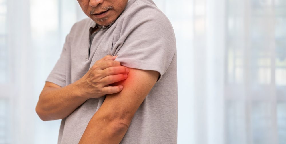 old man scratching his itchy left arm