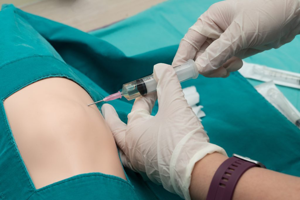 trochanteric bursitis treatment Doctor helping patient with trochanteric bursitis with a needle.