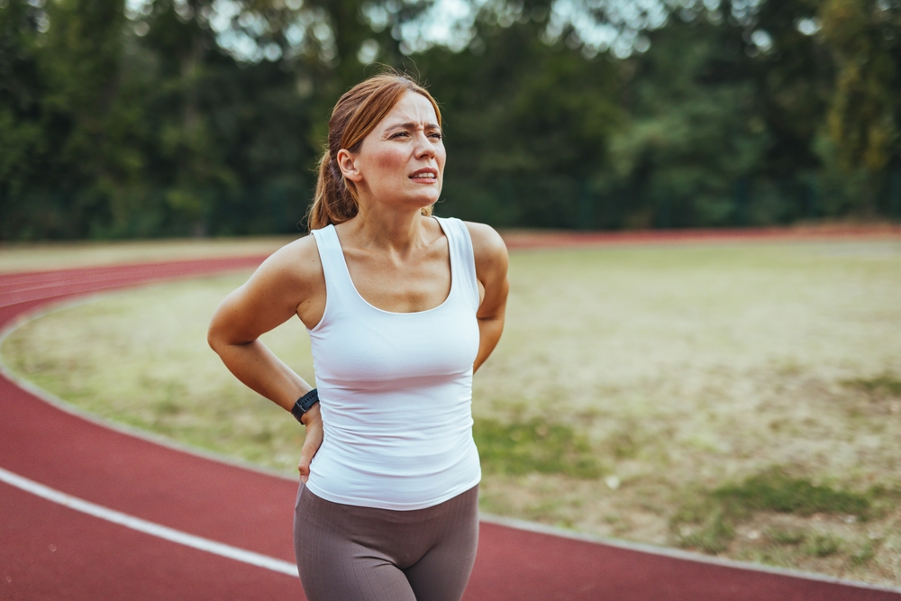 back pain while running. woman experiencing back pain while running.