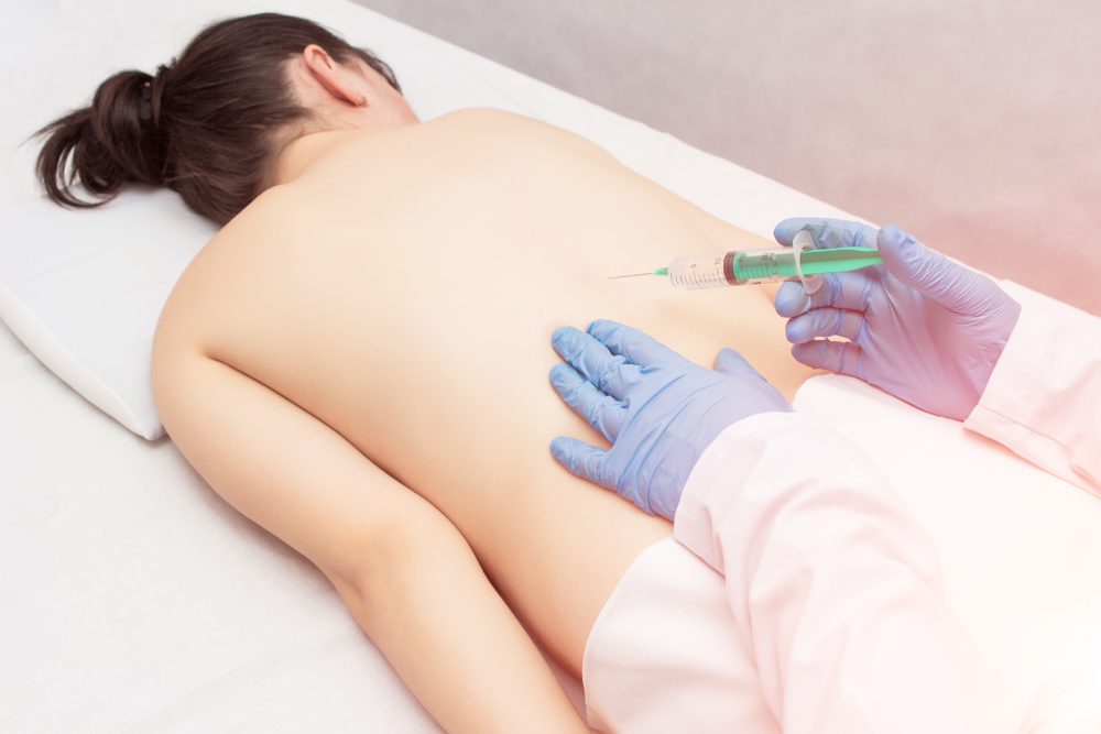 Stem cells for pain. Woman getting stem cells injected into her back to help with chronic pain.